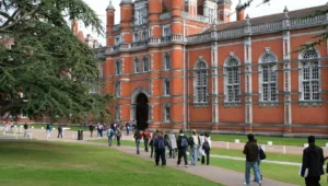 Students walking across a university campus outside a historic academic building, representing college life and student experiences
