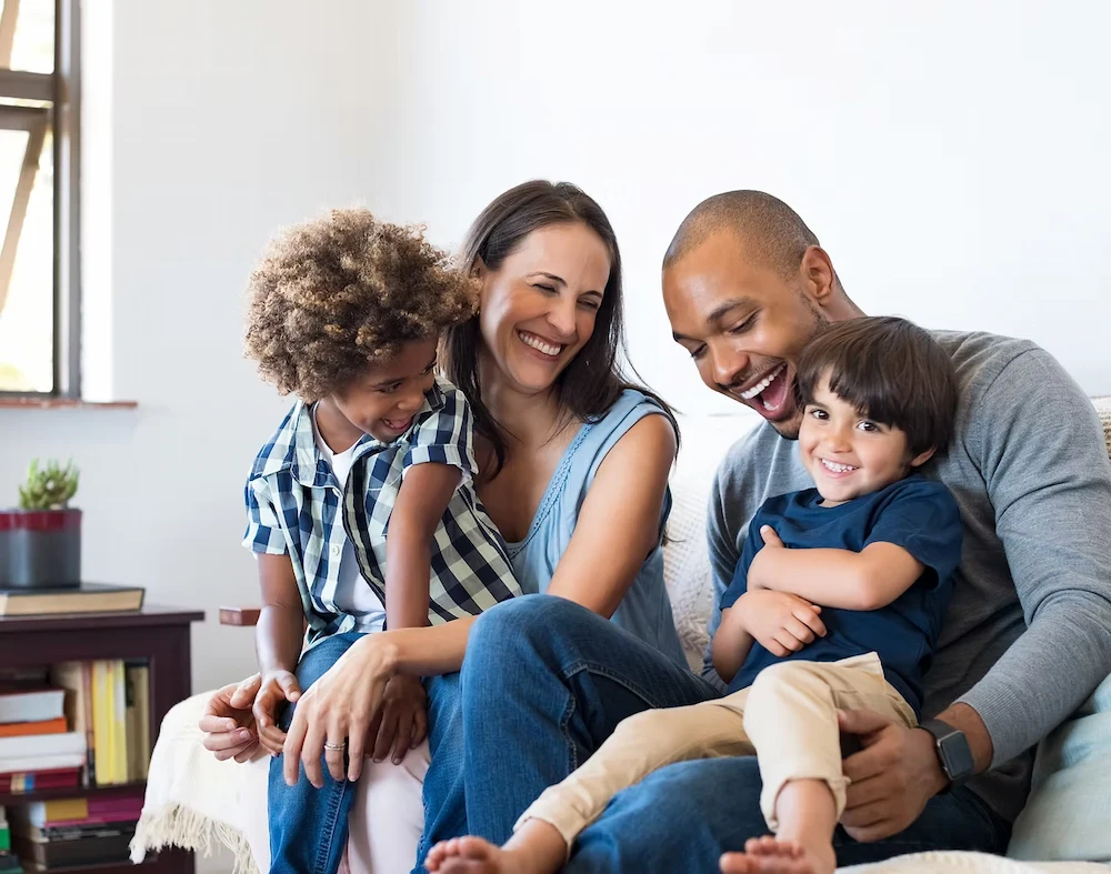 BIPOC family smiling together during a warm moment at home, representing inclusive family therapy and mental health support