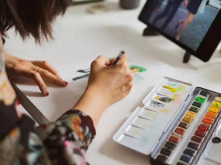 Person painting with watercolors representing art therapy and creative expression for mental health