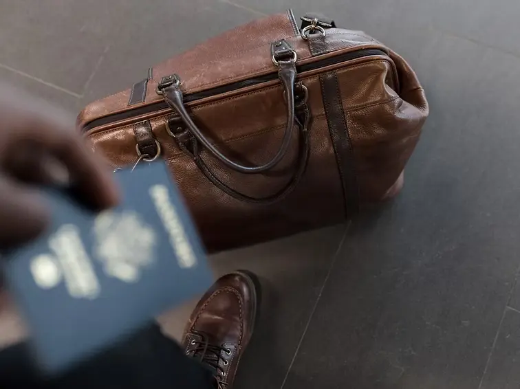 person holding passport near travel bag symbolizing cultural identity and assimilation experience