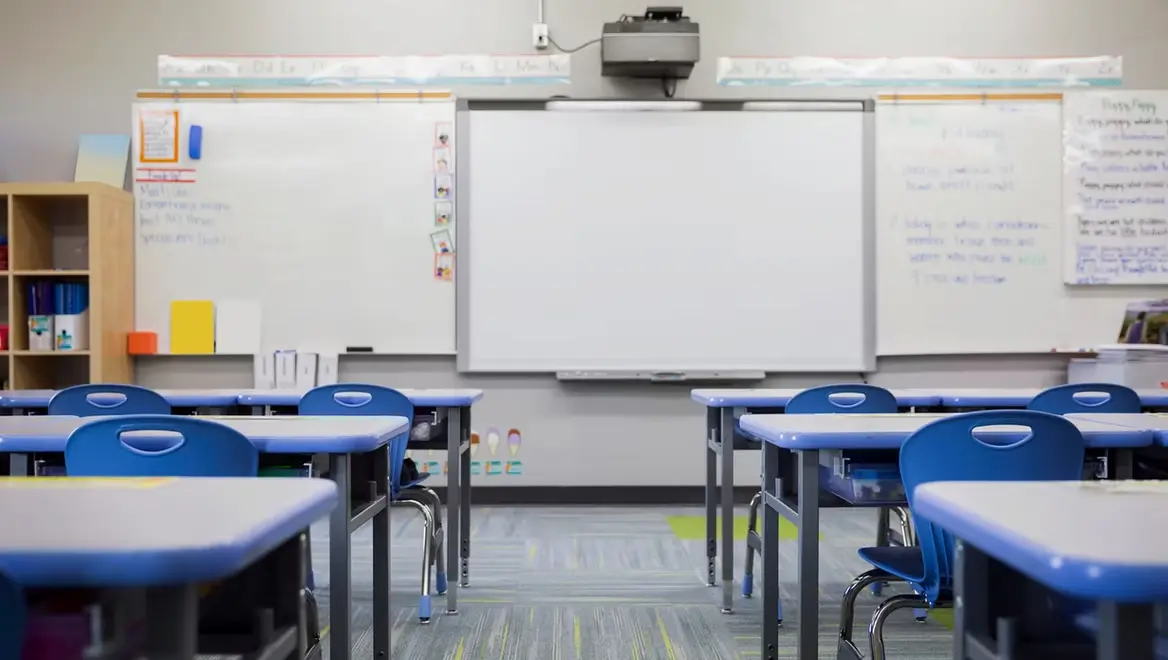 Empty classroom with desks and whiteboard, representing school safety concerns and parenting anxiety in uncertain times