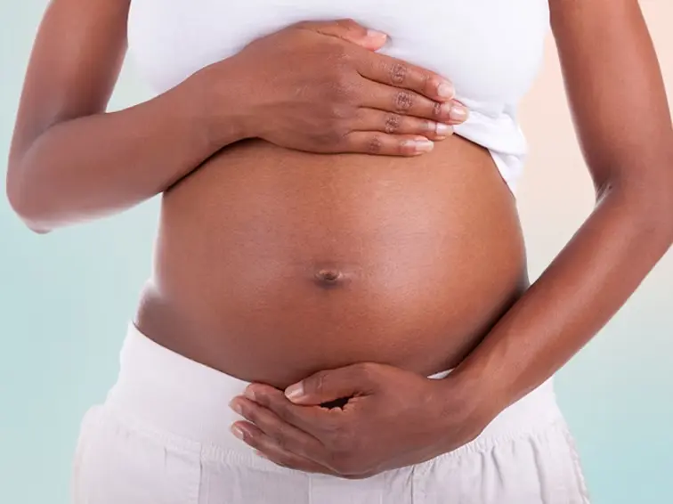Pregnant person holding belly representing postpartum and maternal mental health support