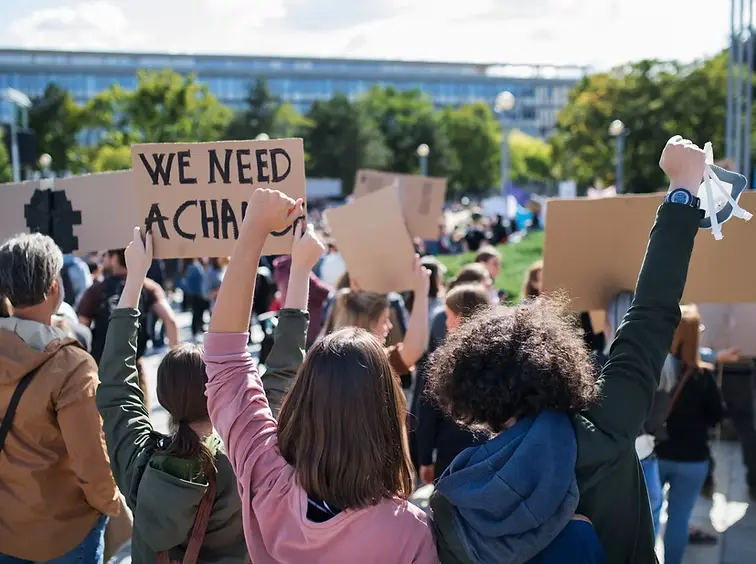 People holding protest signs representing racial justice and the mental health impact of systemic oppression