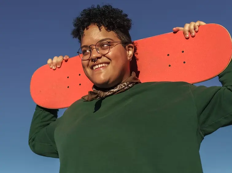Young adult holding skateboard representing identity development and mental health support for teens
