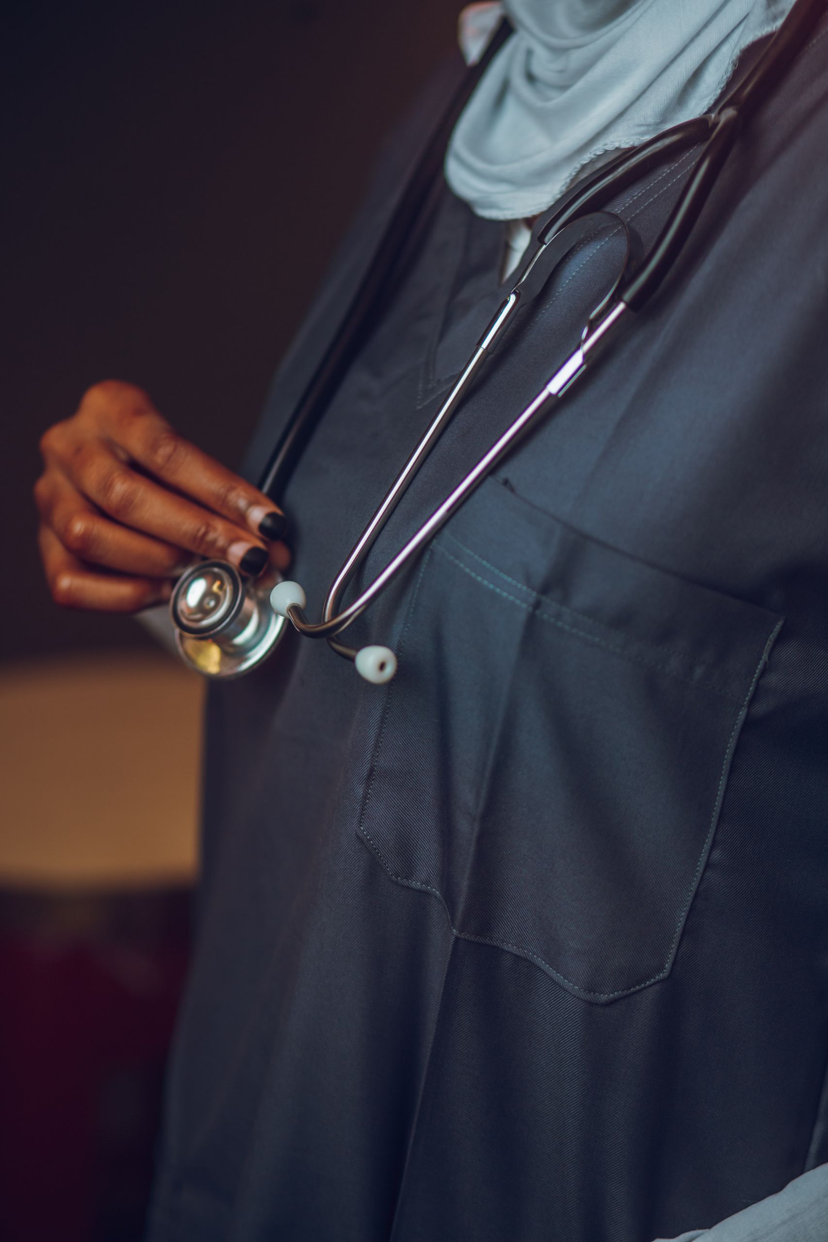 Close-up of a healthcare professional holding a stethoscope, focusing on medical attire and equipment.